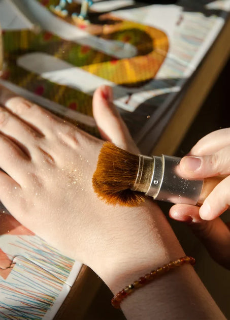 Набір косметики у клатчі золотого кольору: мерехтлива пудра та бальзам для губ